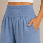 Close-up of stone blue lightweight high-waisted wide-leg lounge pants highlighting the smocked waistband, breathable fabric, and side pocket.
