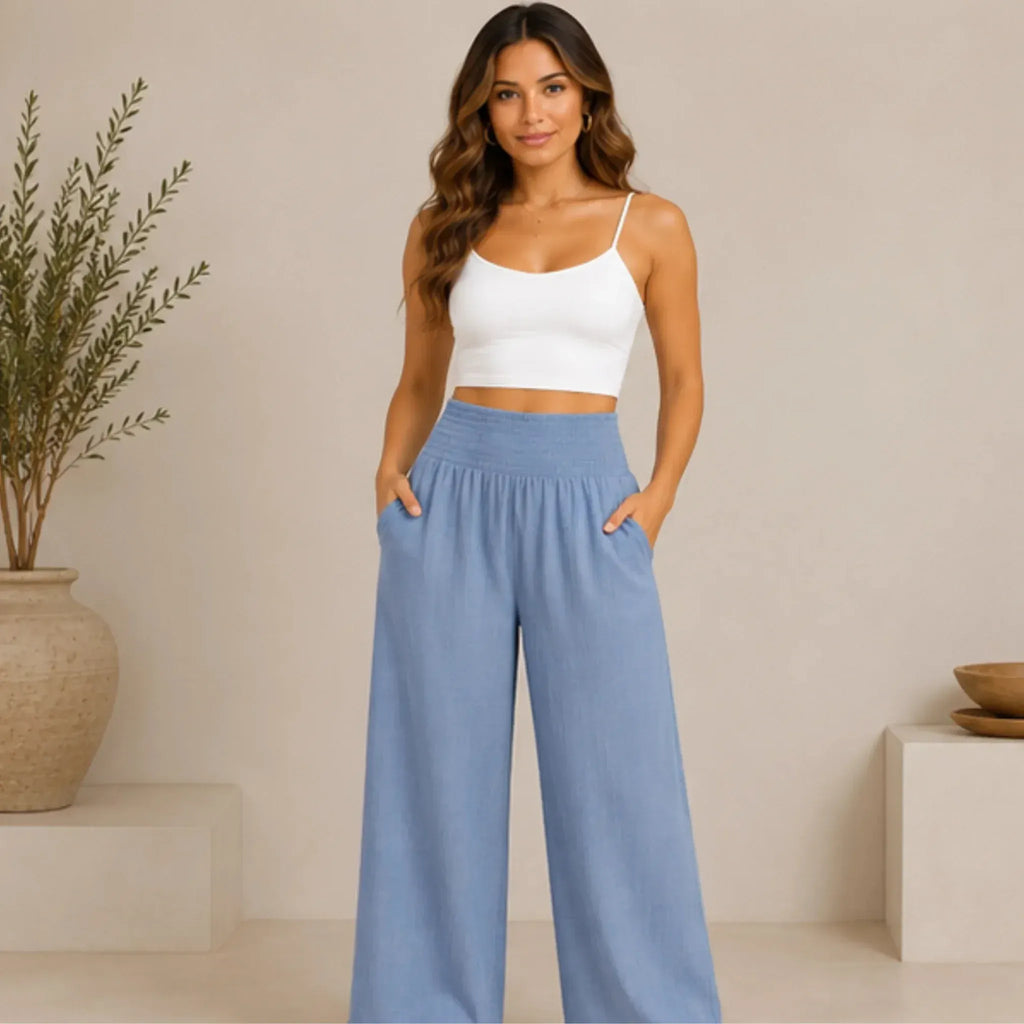 Woman wearing stone blue lightweight high-waisted wide-leg lounge pants with a smocked waistband and side pockets, front view.