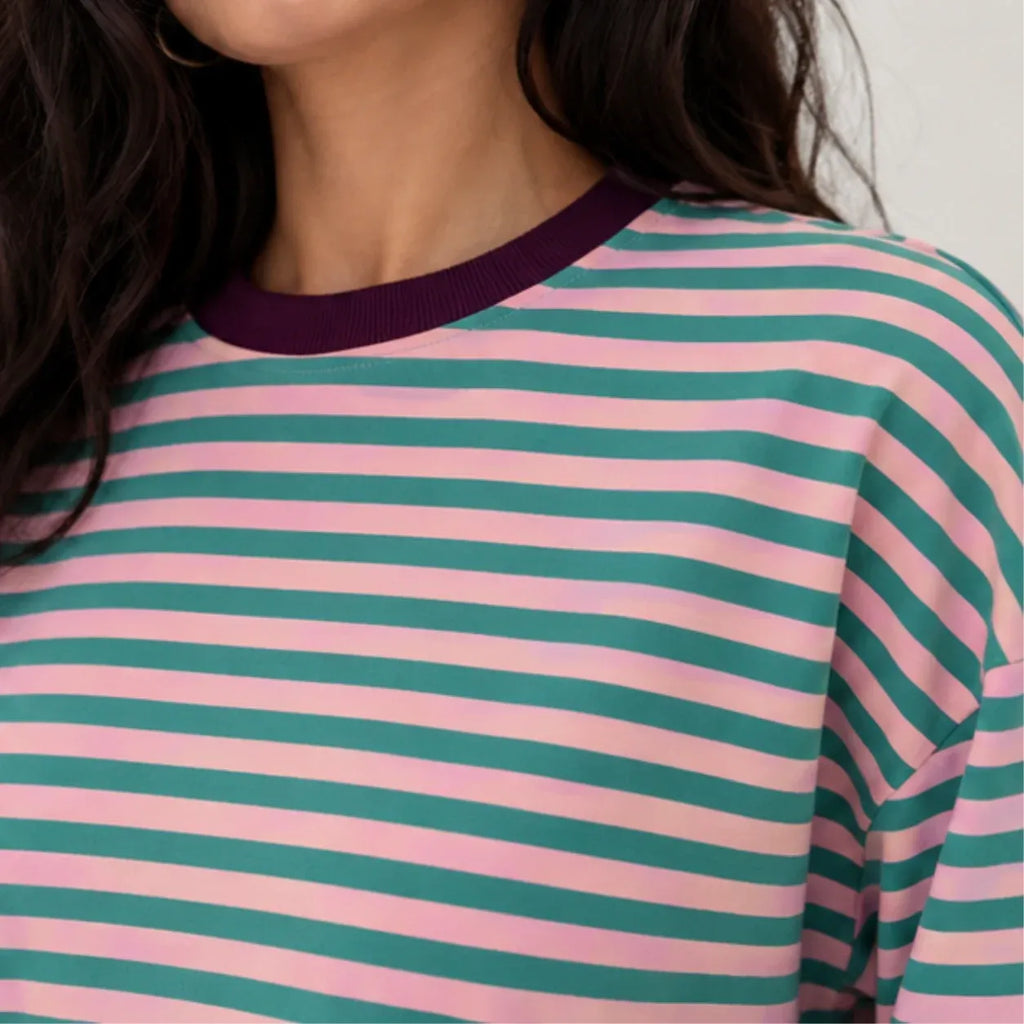Close-up detail of dark purple crewneck collar on pink and teal green striped lounge shirt