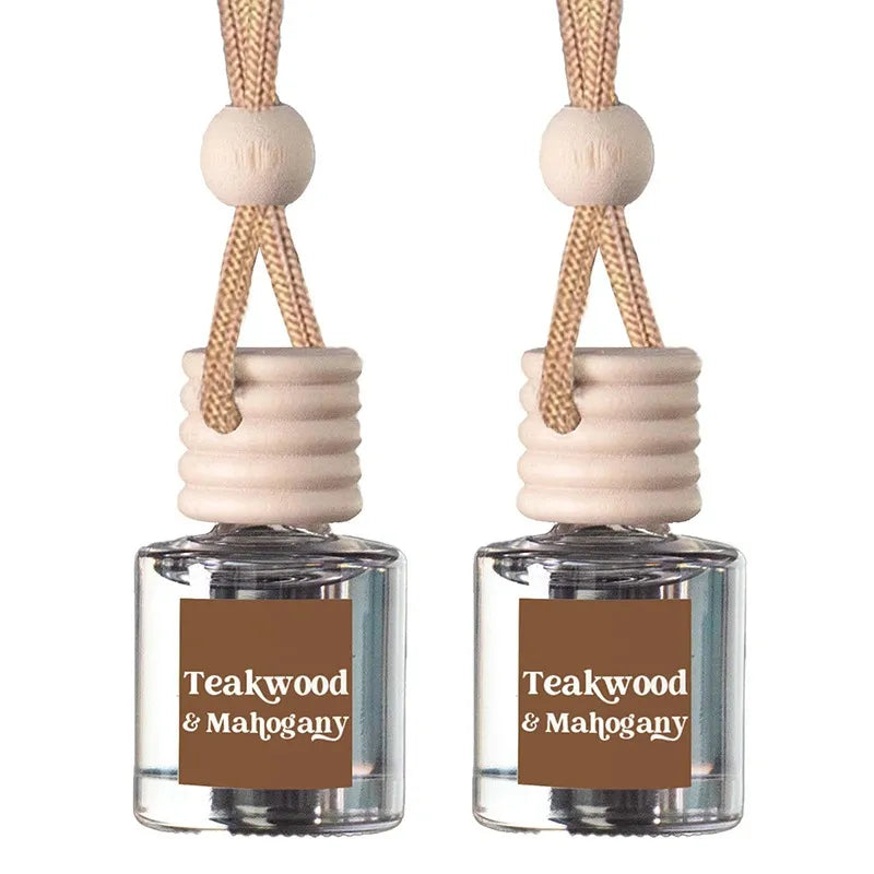Two identical reed diffuser bottles with clear glass bodies, beige wooden stoppers, and natural rope hangers. Each bottle has a brown label reading 'Teakwood & Mahogany' in white text, set against a plain white background.
