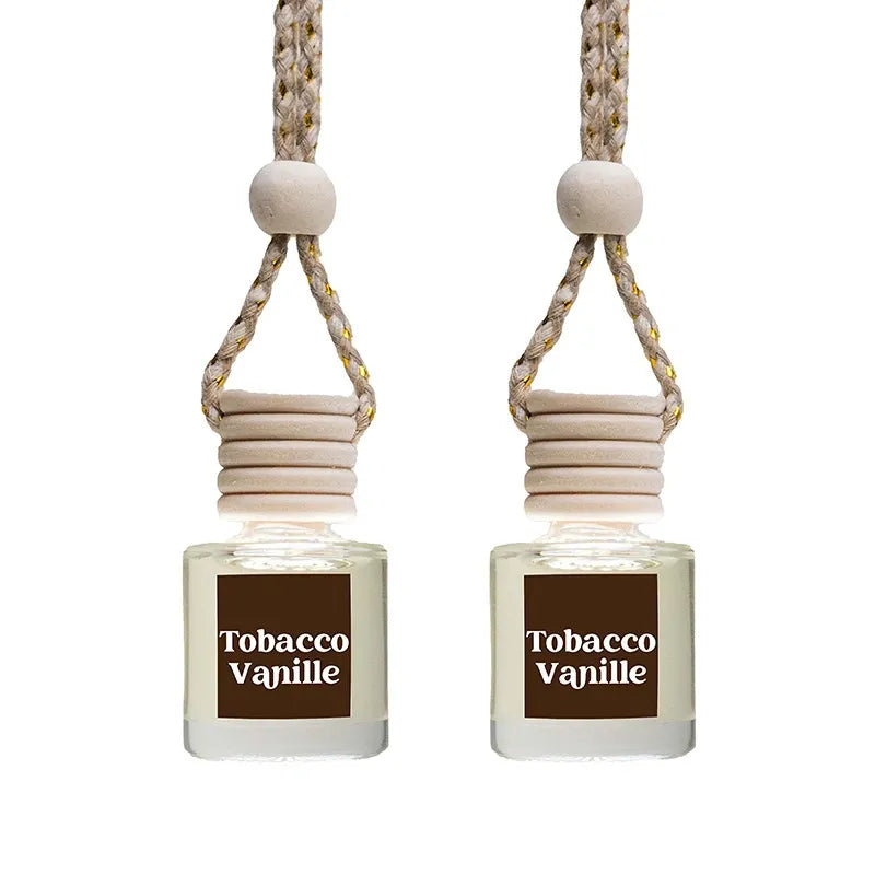 Two Tobacco Vanille reed diffusers with clear glass bottles, light wood reeds, and a beige braided hanging cord on a white background.