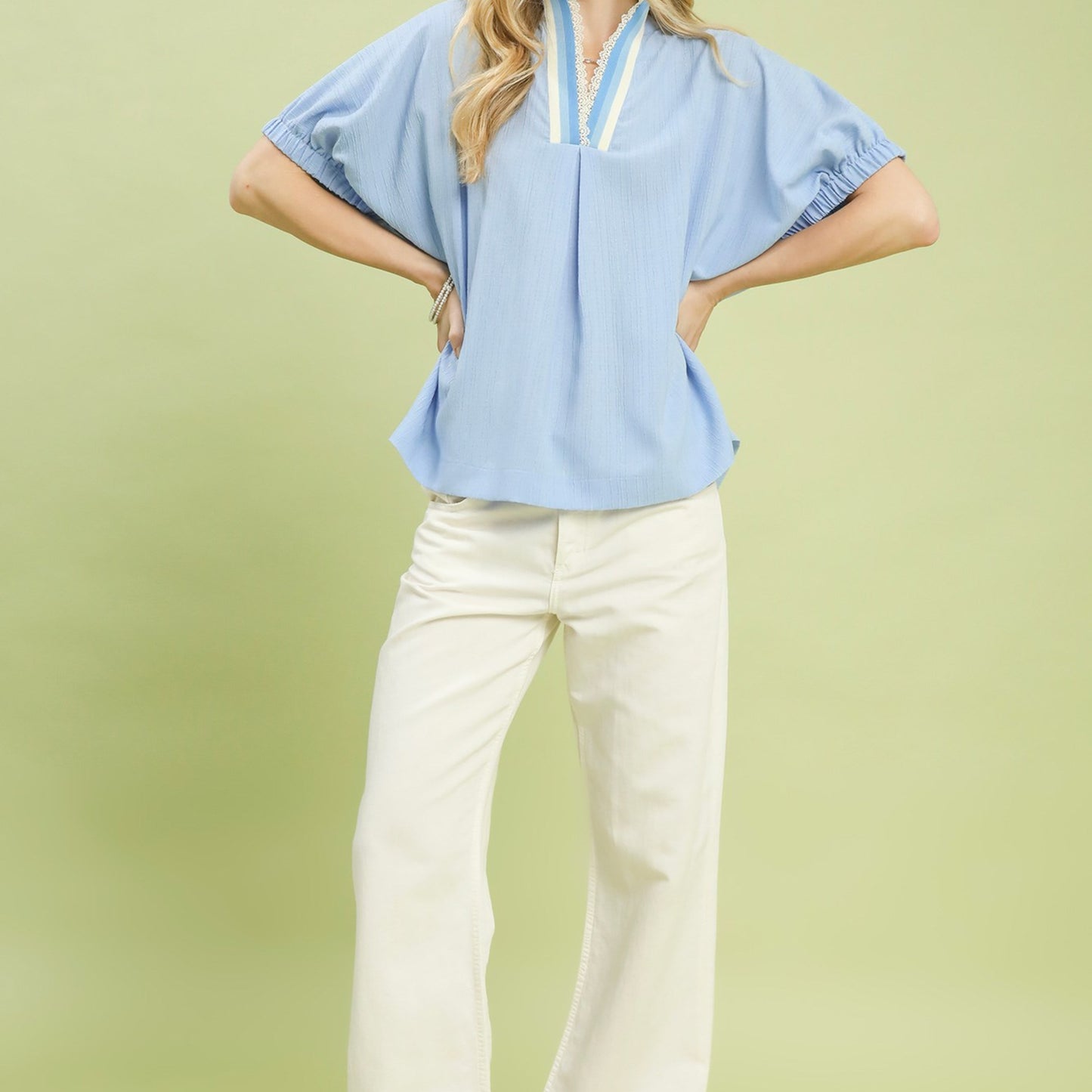 Lifestyle shot of the light blue textured V-neck blouse for an elegant daytime look.