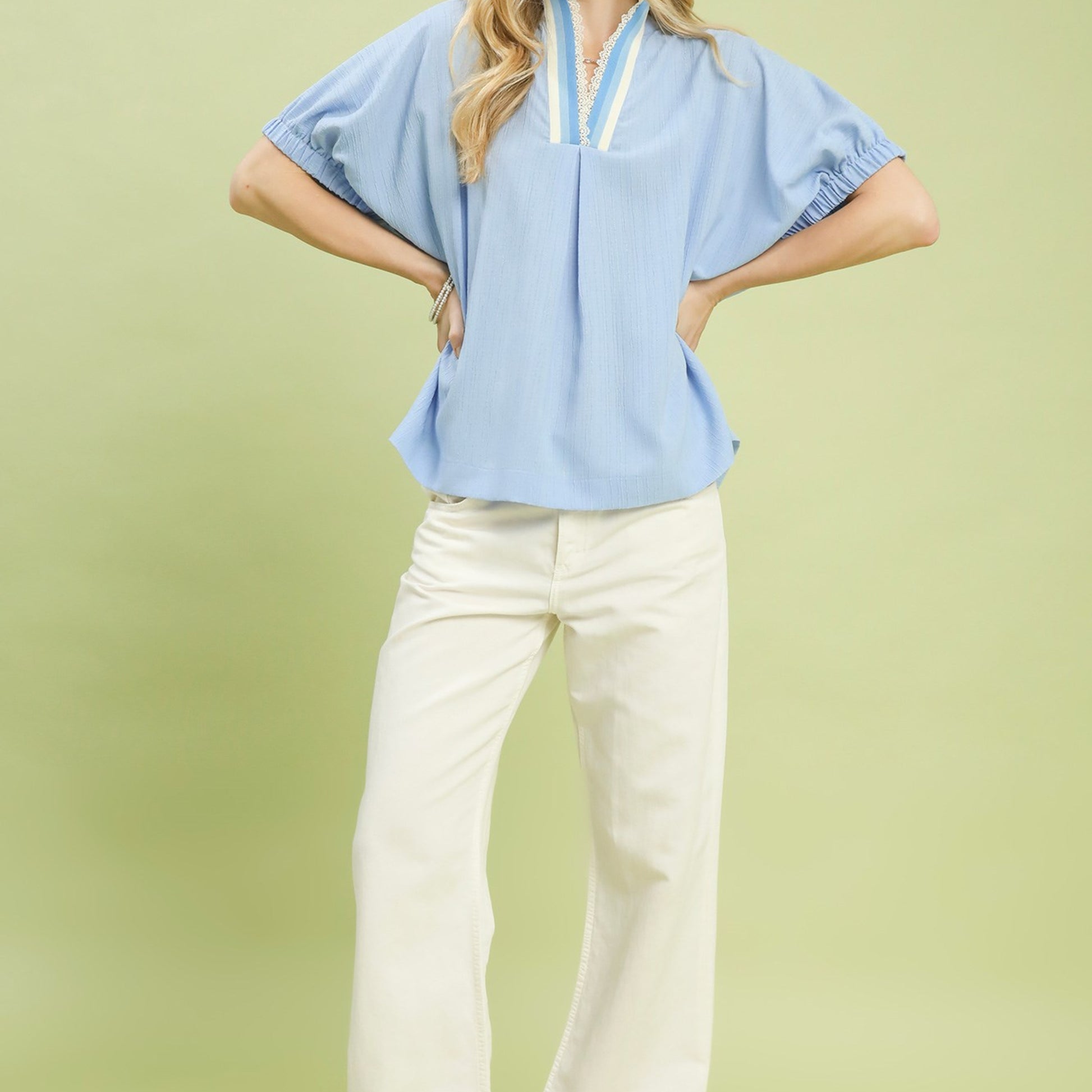Lifestyle shot of the light blue textured V-neck blouse for an elegant daytime look.