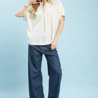 Lifestyle shot of the cream textured V-neck blouse for a sophisticated daytime look.