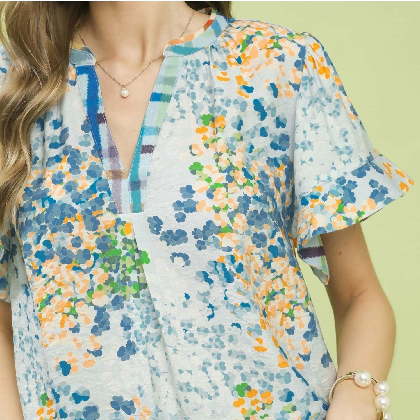 Close-up of the notched neckline and delicate flutter sleeve detail on the boho print top.