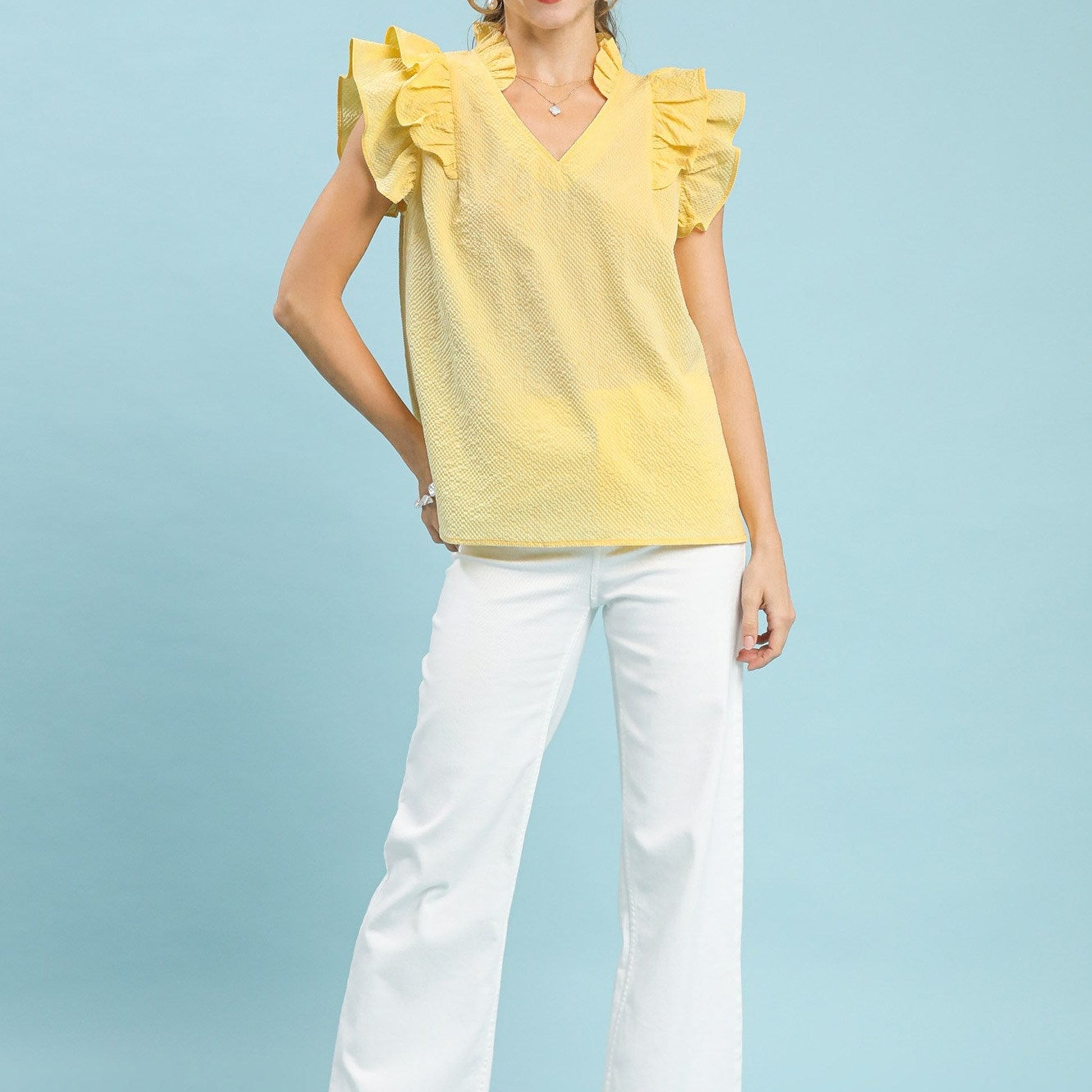 Lifestyle shot of the ice lemon textured blouse paired with white pants.