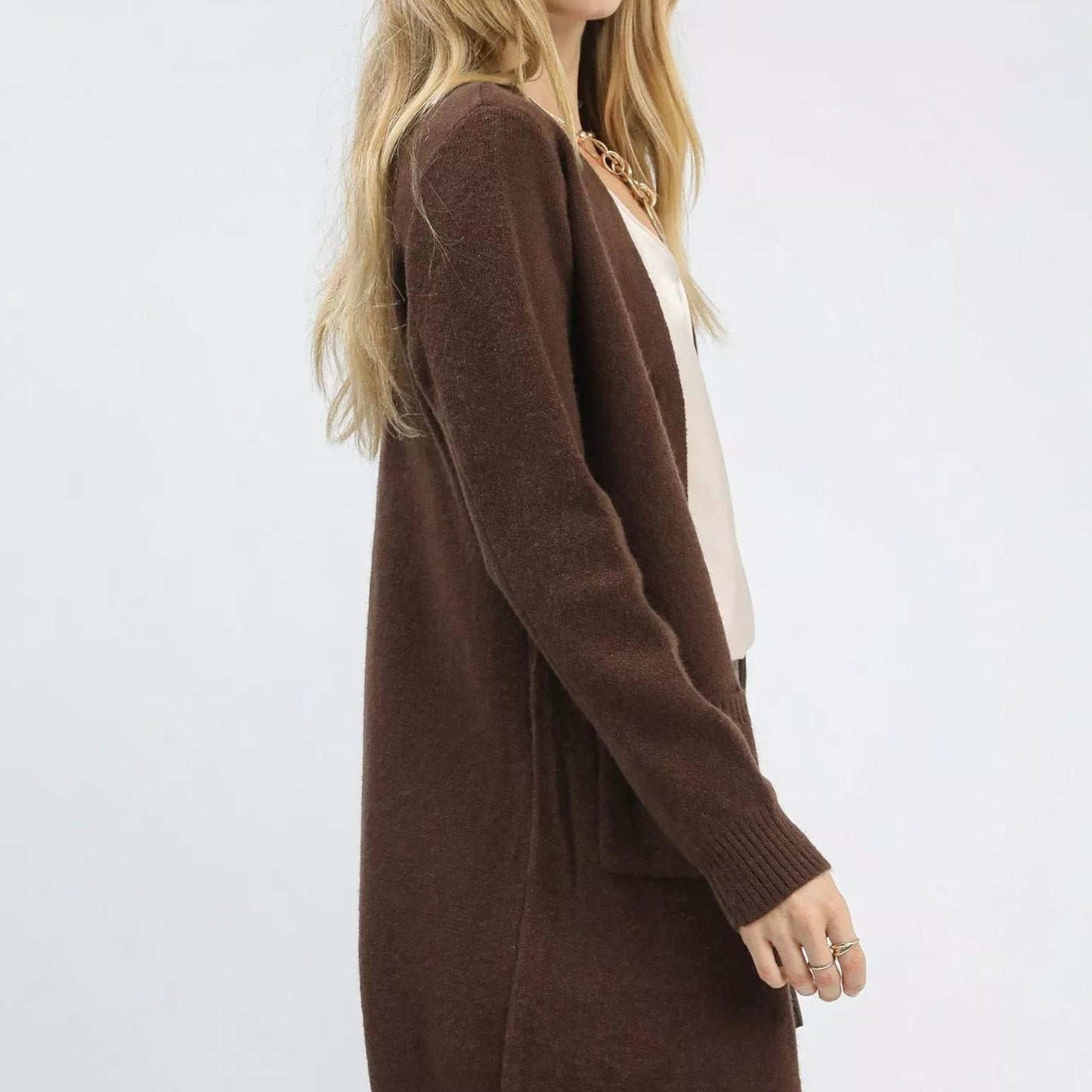 Side profile of an Umgee longline V-neck sweater in brown, highlighting the relaxed fit and ribbed cuff detailing.