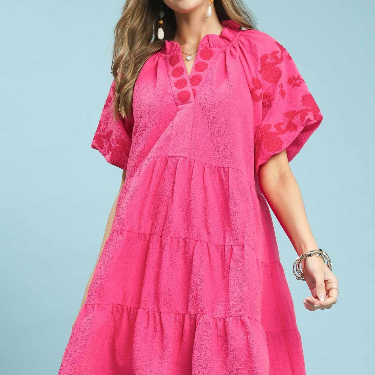 Woman wearing a pink dress with floral patterns on a light blue background