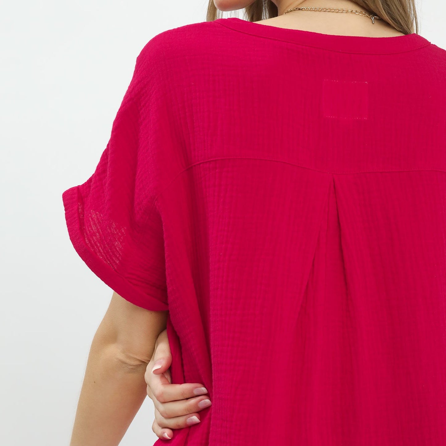 Close-up of the buttoned split-neck and delicate embroidery on the red gauze top.