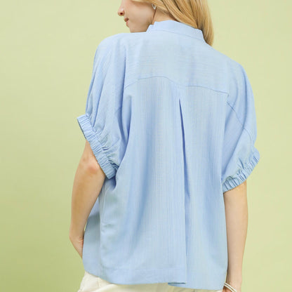 Back view of the women's light blue textured blouse highlighting the sleek finish.