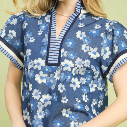 Close-up of the V-neckline and the mustard-colored cuffed dolman sleeves on the floral blouse.