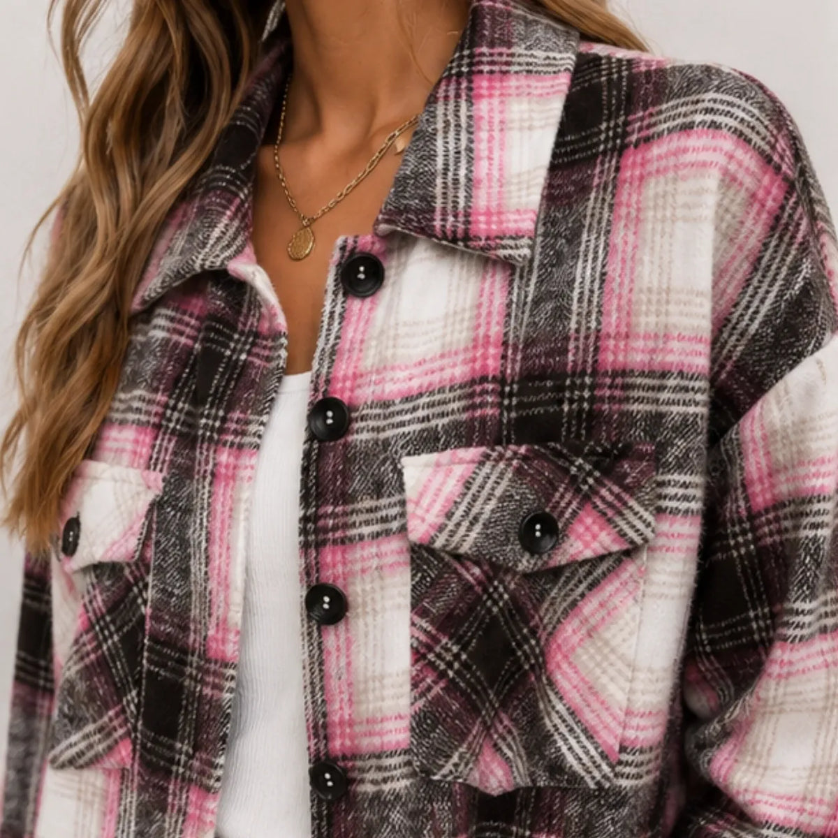 Close-up of pink and black plaid long cardigan shirt jacket showing button front and flap pockets
