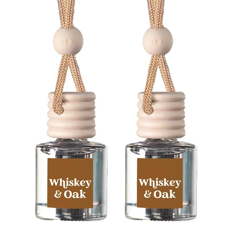 Two matching whiskey and oak car air fresheners with clear glass bottles, beige wooden diffusers, and braided rope hangers on a white background.