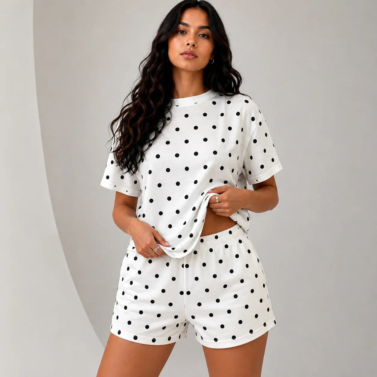 Woman wearing white short-sleeve top and matching lounge shorts set with black polka dots