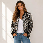 Woman wearing a black and tan leopard print bomber jacket with a white tank top and jeans