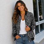 Woman wearing a black and white leopard print bomber jacket with a white tank top and jeans