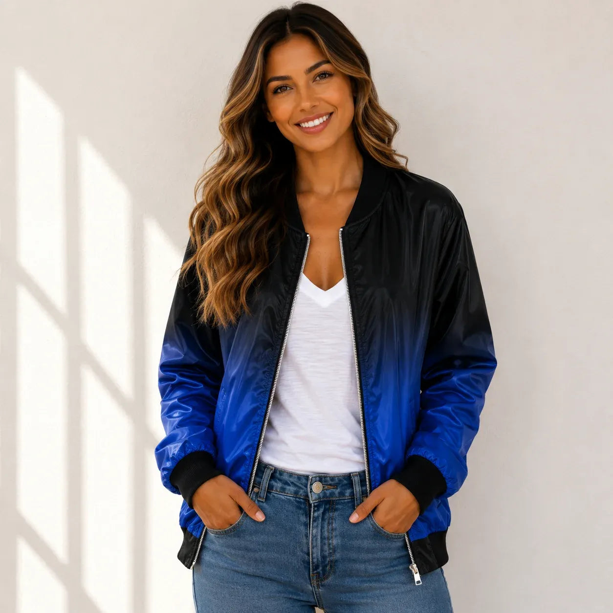 Woman wearing a blue and black bomber jacket with a white tank top and jeans