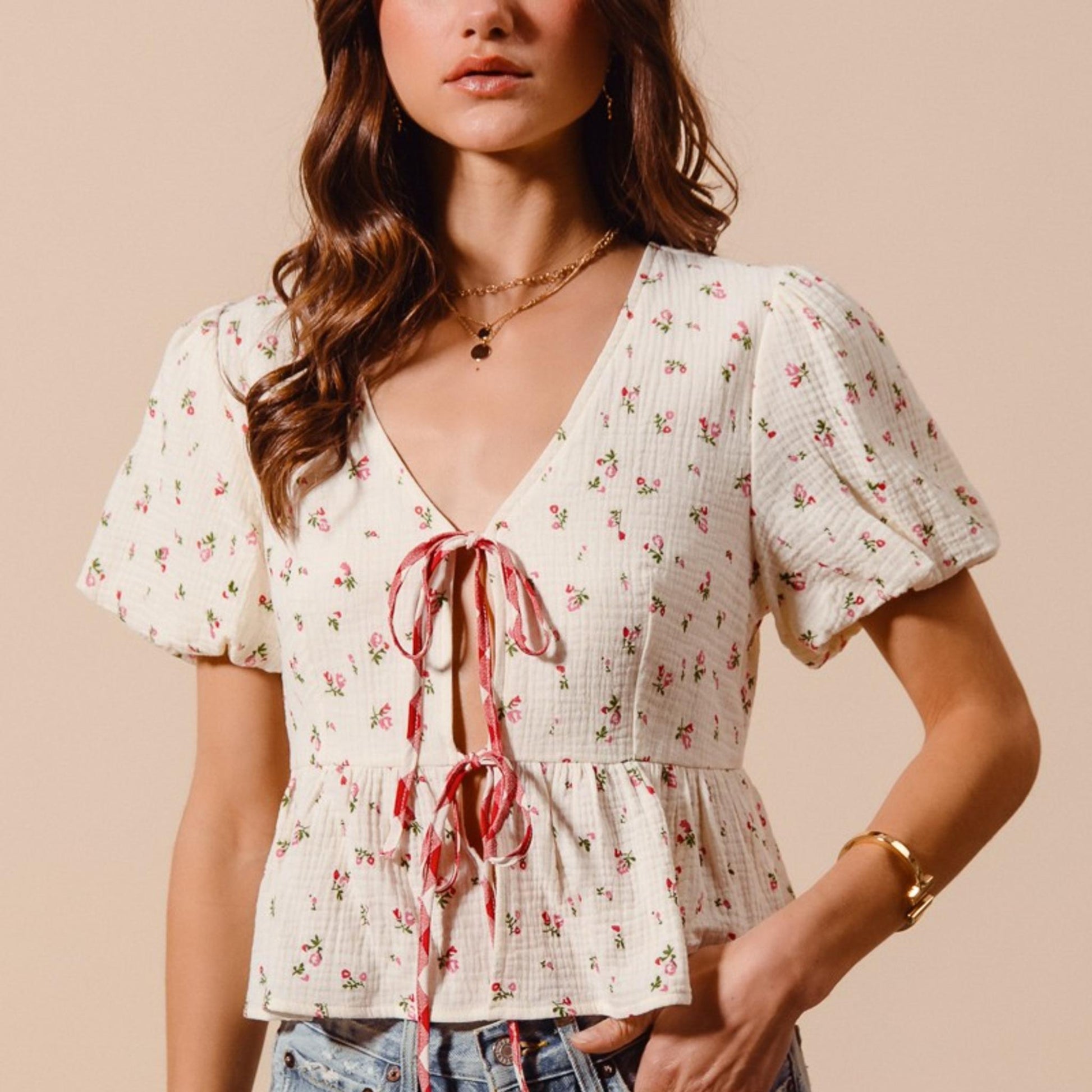 Lifestyle photo of the ivory and red check floral tie-front blouse styled with high-waisted jeans for a boho look.