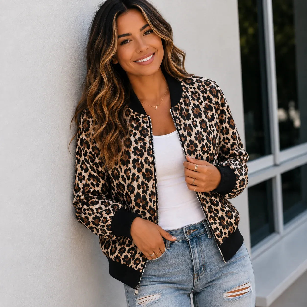 Woman wearing a brown and tan leopard print bomber jacket with a white tank top and jeans