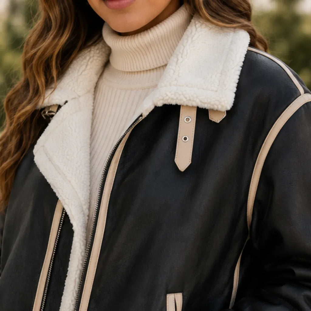 Close-up of women's black faux leather jacket showing plush shearling collar and cream trim