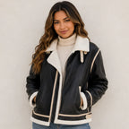 Women's black faux shearling-lined leather jacket with plush collar, cream trim, and zip front