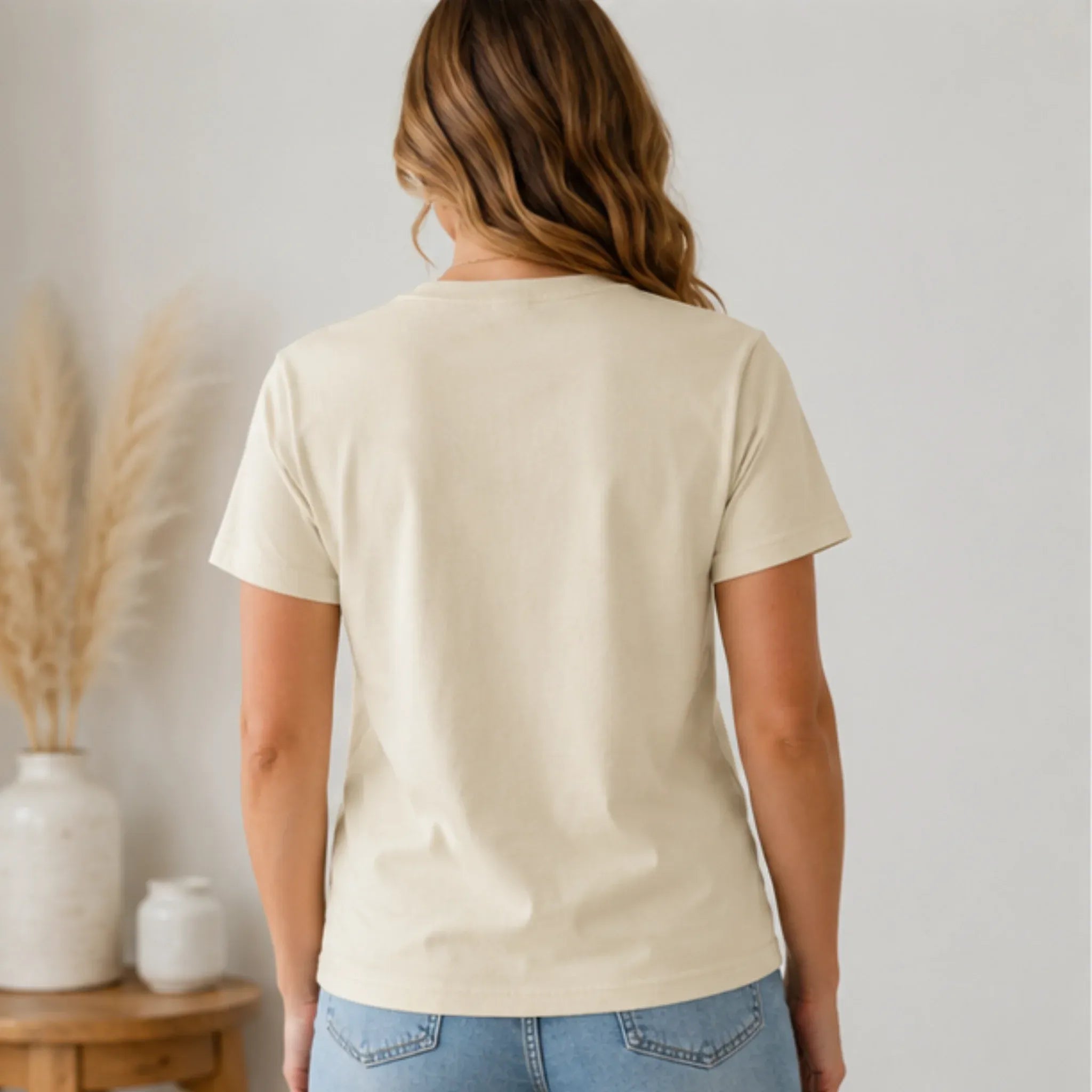 Back view of Women's Floral American Flag Graphic Tee in cream styled with light wash denim jeans.