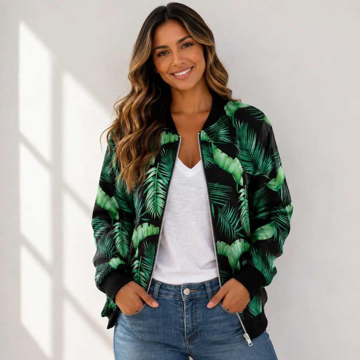 Woman wearing a green monstera leaf print bomber jacket with a white tank top and jeans