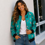 Woman wearing a turquoise butterfly print bomber jacket with a white tank top and jeans