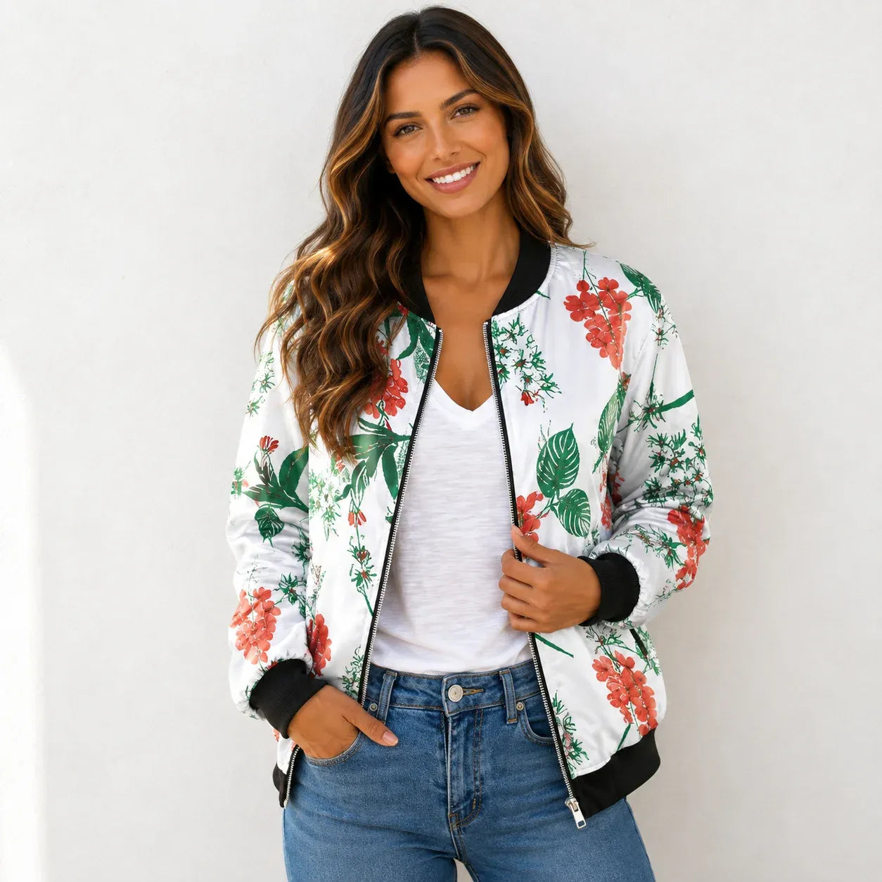 Woman wearing a white tropical floral bomber jacket with a white tank top and jeans