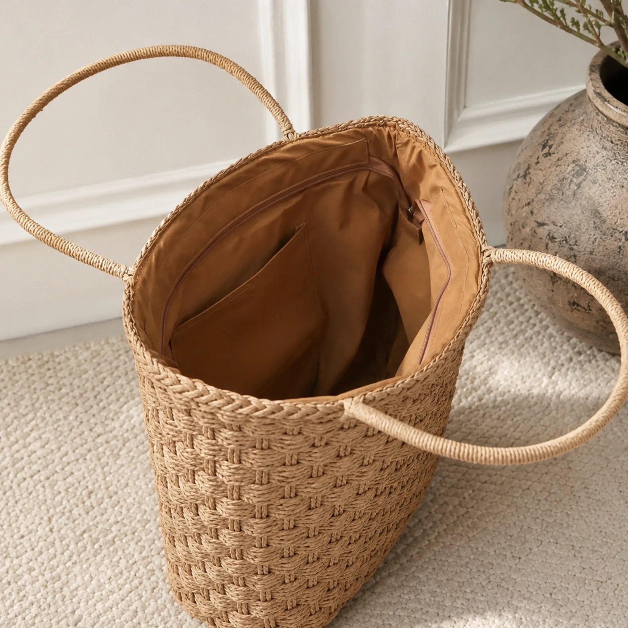 Interior of a woven straw tote bag featuring a zip pocket, slip pockets, and spacious lined compartment.