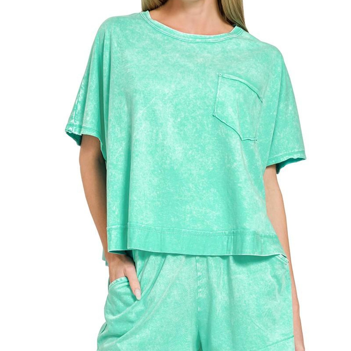 Woman wearing a mint green outfit with a top and shorts on a white background