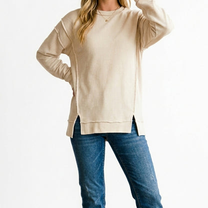 Lifestyle image of the distressed exposed-seam sweatshirt in Sand Beige.